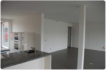 Strak gestucte woonkamer met open keuken, witte wanden en een egaal wit plafond